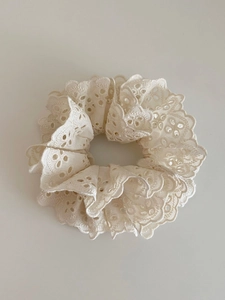 Gros plan d'un chouchou en dentelle crème avec motif floral évidé à double couche
