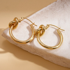 Vue macro de boucles d'oreilles nœud dorées sur pierre montrant le fini métallique