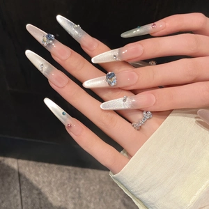 Détail de faux ongles amande longs avec paillettes argentées et gemmes colorées