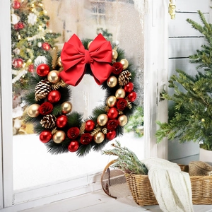 Couronne de Noël avec nœud rouge, pommes de pin et boules dorées sur fenêtre enneigée