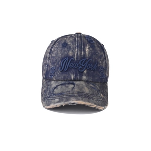 Detail of distressed denim baseball cap featuring New York embroidery and frayed edges