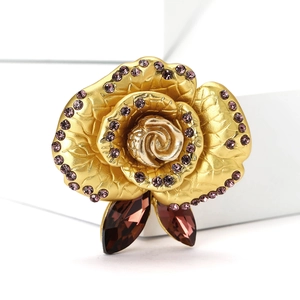 Detail of golden rose brooch featuring purple rhinestones and marquise gemstone leaves