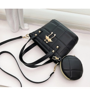 Close-up of black quilted tote bag with golden swan charm and matching round coin purse