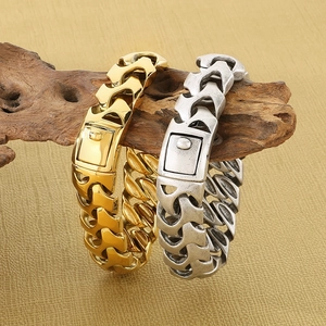 Détail des bracelets chaîne de dragon en or et argent sur un support en bois naturel