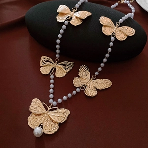 Detail of vintage butterfly pearl necklace with gold charms on black pebbles