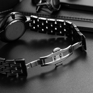 Macro shot of black stainless steel butterfly buckle and chain strap on a business watch