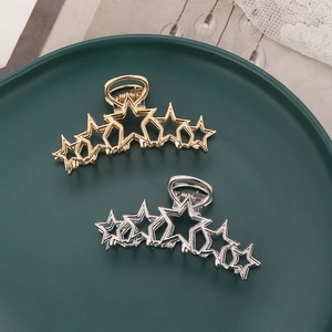 Detail shot of hollow star-shaped gold and silver hair claws on a green plate