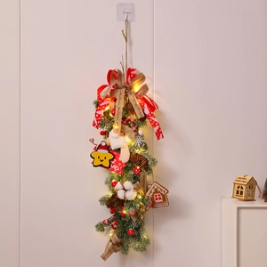 Detail of Christmas garland with LED lights, Santa doll, pine cones and berries on wall