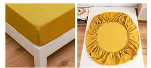 Detail of yellow fitted sheet with elastic band showing snug fit on mattress corners