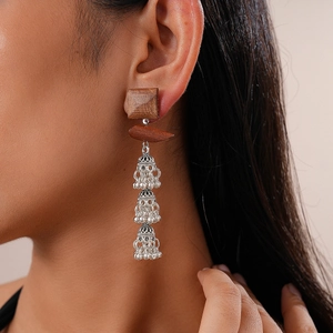 Detail of bohemian drop earrings featuring square wood blocks and silver jhumka bells