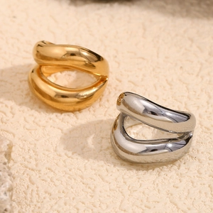 Minimalist lip-shaped wave rings in 18K gold and silver finishes on a stone base