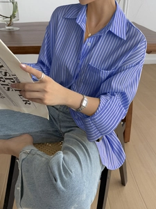 Close-up of blue and white striped long sleeve shirt with rolled cuffs and button detail