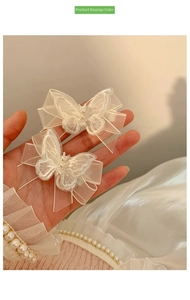 Macro view of white mesh butterfly hair clips with delicate embroidery and pearl details