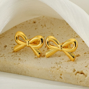 Macro shot of gold bow stud earrings featuring a polished mirror finish and minimal design