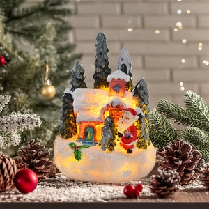 Close-up of lighted Christmas resin house with Santa Claus and warm LED glow