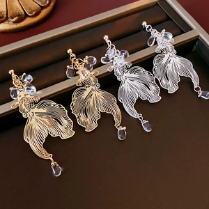 Detail of gold and silver koi fish earrings with transparent crystal beads on tray