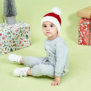Detail of child wearing thick knit Christmas hat with pompom and warm winter sweater