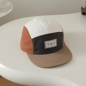 Dettaglio cappello 5-panel per bambini con patch TIDE e cuciture color block vivaci