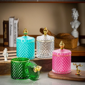 Detailed close-up of diamond-cut glass storage jars in blue, green, and pink with gold lids