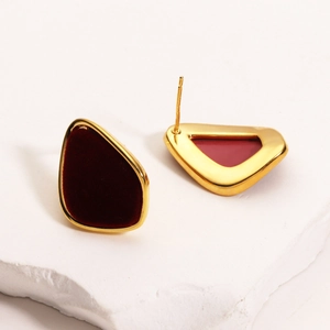 Close-up of geometric 18K gold plated earrings with burgundy flocking on a stone base