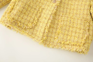 Macro view of fringe hem detail on a yellow tweed jacket for women with fabric texture