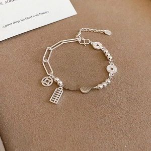 Detailed view of silver bracelet with vintage Chinese coin and abacus charms