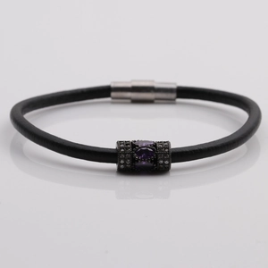 Macro detail of black leather bracelet with purple stone inlay and magnetic clasp