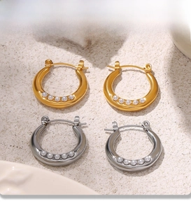 Detail of PVD electroplated gold and silver pearl hoop earrings on beige background