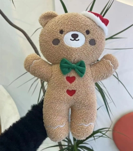 Close-up of a gingerbread style brown teddy bear plush with Christmas hat and green bowtie