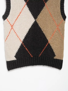 Detail of classic argyle knit vest featuring black and beige patterns with ribbed armholes