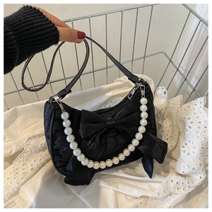 Close-up of black pleated bag featuring a large satin bow and decorative pearl handle