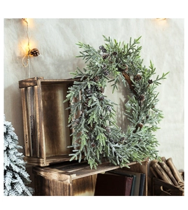 Close-up of frosted Christmas wreath with pine cones leaning on a rustic wooden box