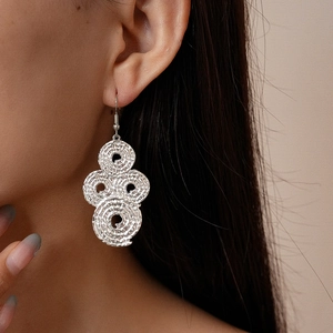 Detailed close-up of silver pleated geometric drop earrings worn by a model