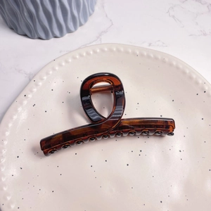 Detail of amber tortoiseshell large hair claw clip on white ceramic plate
