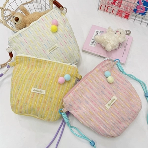 Three colorful knitted crossbody phone bags with fuzzy balls and adjustable straps