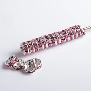 Dettaglio macro di distanziatori argentati con strass rosa per gioielli fai-da-te