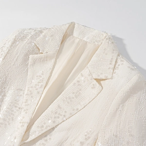 Dettaglio del risvolto del blazer di paillettes avorio con texture scintillante