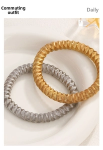 Detailed view of gold and silver twisted stainless steel bangles on a ceramic plate