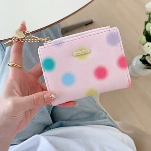 Pink women's short wallet with colorful polka dots and heart pendant in soft lighting