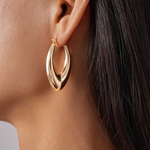 Close-up of elegant gold hollow teardrop earrings worn on model for a modern look