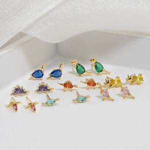 Macro detail of 18K gold dinosaur stud earrings with colorful zircon inlay settings