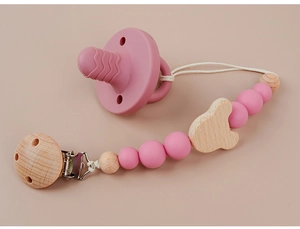 Detail of pink silicone pacifier and wooden bear clip chain on flat background