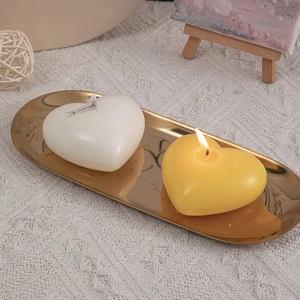Romantic heart-shaped scented candles in white and yellow on a gold tray for home decor