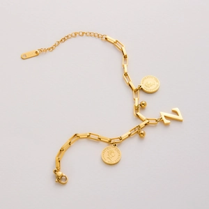 Detail of gold-plated stainless steel bracelet with N pendant and coin charm