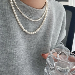 Double-layered white pearl necklace in titanium steel worn with casual grey outfit