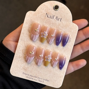 Detailed view of handmade almond press-on nails with purple gradient and 3D floral pearls