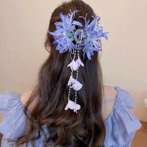 Détail de la pince à cheveux en tissu violet avec de longs glands sur cheveux bruns