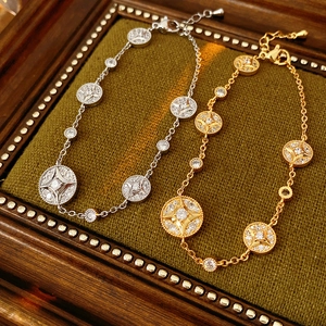 Detailed macro view of 18K gold and silver starburst charm bracelets on green velvet