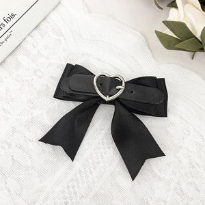 Detail of gothic black satin bow hair clip with silver heart buckle and leather strap