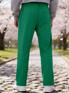 Detail view of green men's joggers showing elastic waistband and back pocket in a park